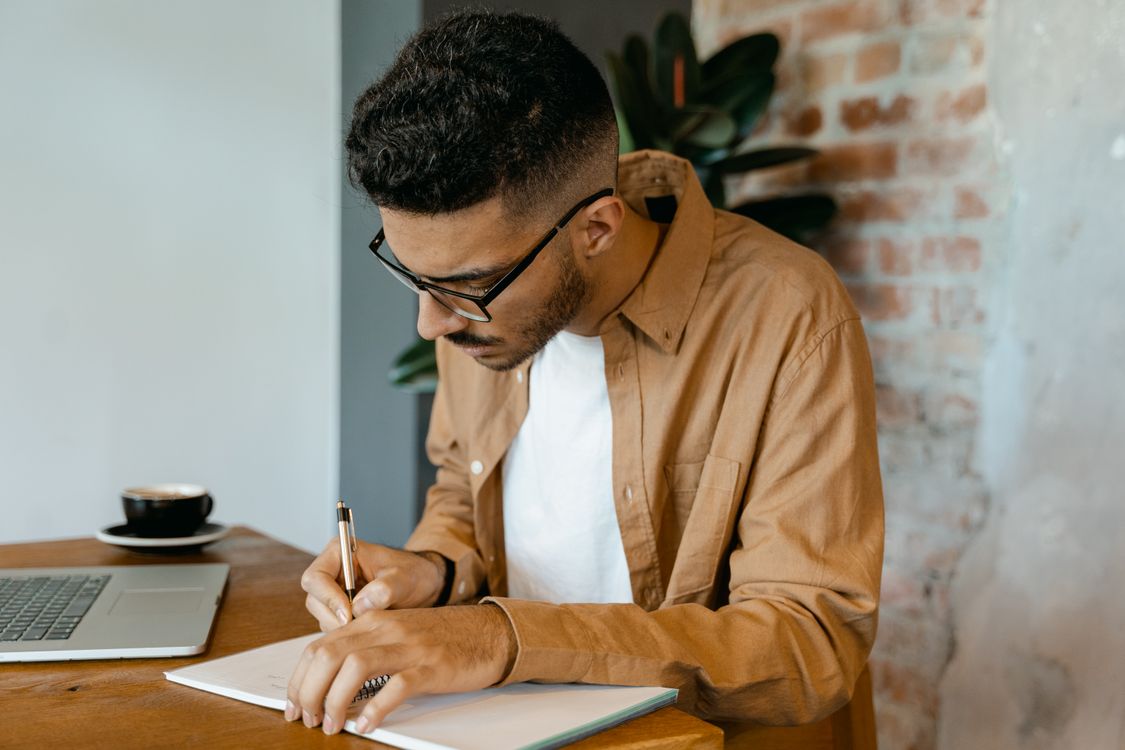 Un homme en chemise sobre prend des notes avec attention dans un carnet.