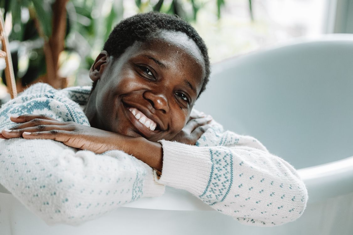 Une femme souriante se repose chez elle dans un pull douillet.